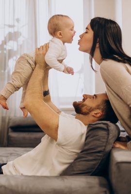 Young family with toddler baby daughter sitting on coach at home